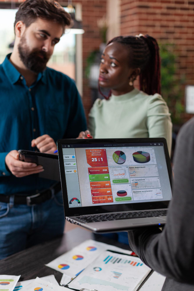 ABOUT WPGIO IT SOLUTIONS 2 multiracial businesspeople analysing company turnover discussing business collaboration while working brick wall startup office mult ethnic team brainstorming ideas marketing project