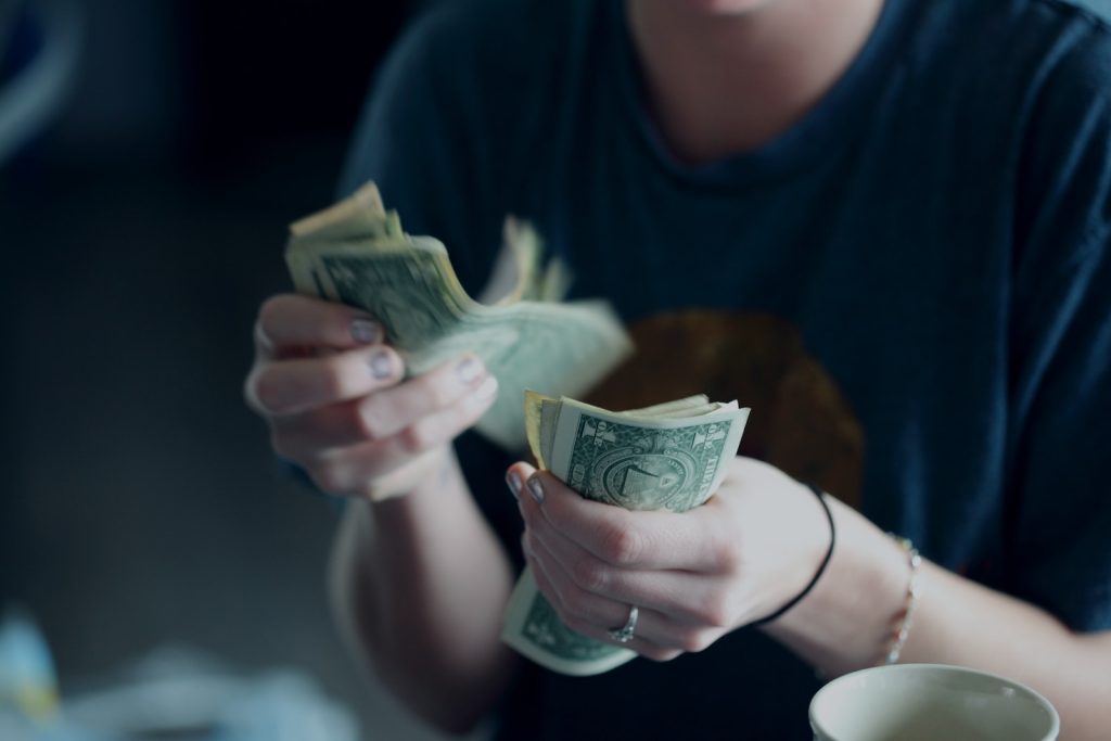 Scribie Review focus photography of person counting dollar banknotes