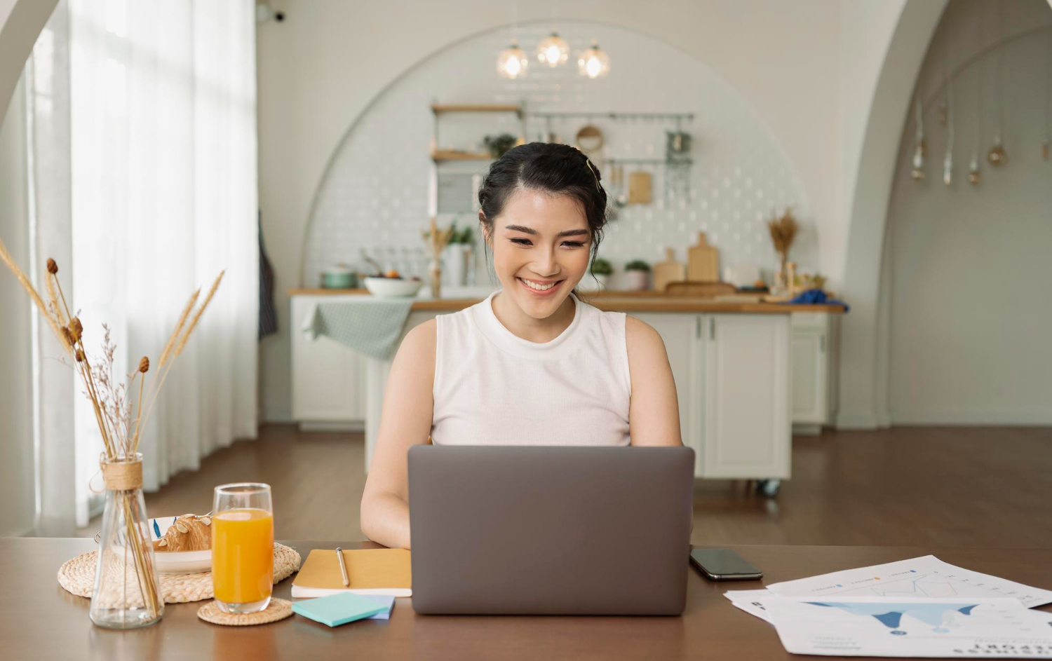 beautiful young asian woman working laptop computer while sitting kitchen room background