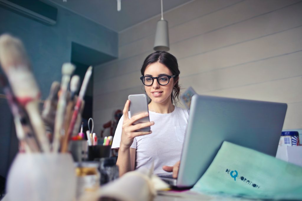 images to promote your brand on social media woman in white shirt using smartphone