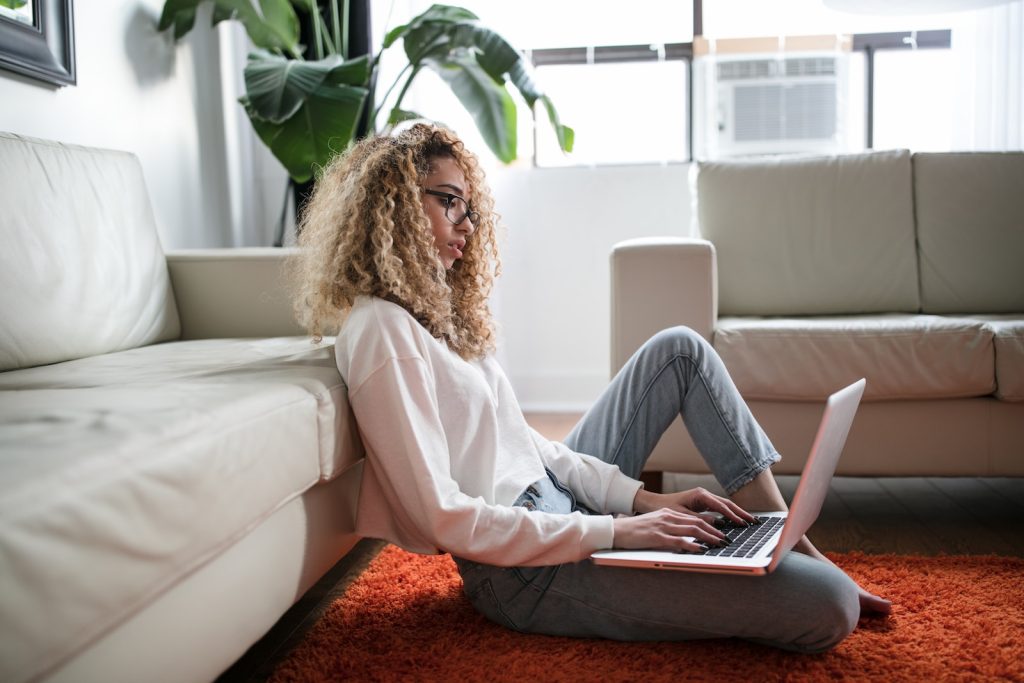 Apple At Home Advisor Review woman sitting on floor and leaning on couch using laptop