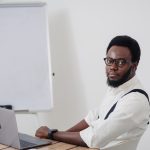 a man sitting at a table with a laptop in front of him